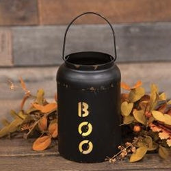 Black lantern with 'BOO' on it, surrounded by autumn leaves on a wooden surface.