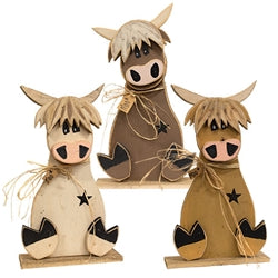 Three decorative wooden cow figurines with star patterns on a white background