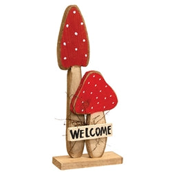 Wooden mushroom decoration with red caps and 'Welcome' sign on a white background