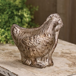 Resin chicken figurine on a wooden surface with blurred greenery in the background