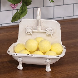 Decorative bathtub with yellow soap balls and a faucet on a wooden surface.