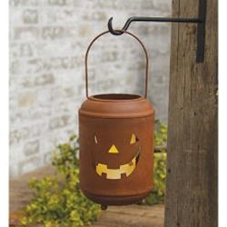 metal pumpkin lantern with jack-o'-lantern face on a wooden post outdoors.