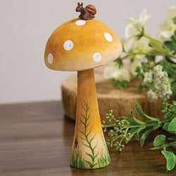 Decorative mushroom with polka dot pattern on a wooden surface with flowers in the background