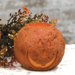 Decorative pumpkin LED candle with a carved face on a wooden surface with a blurred background