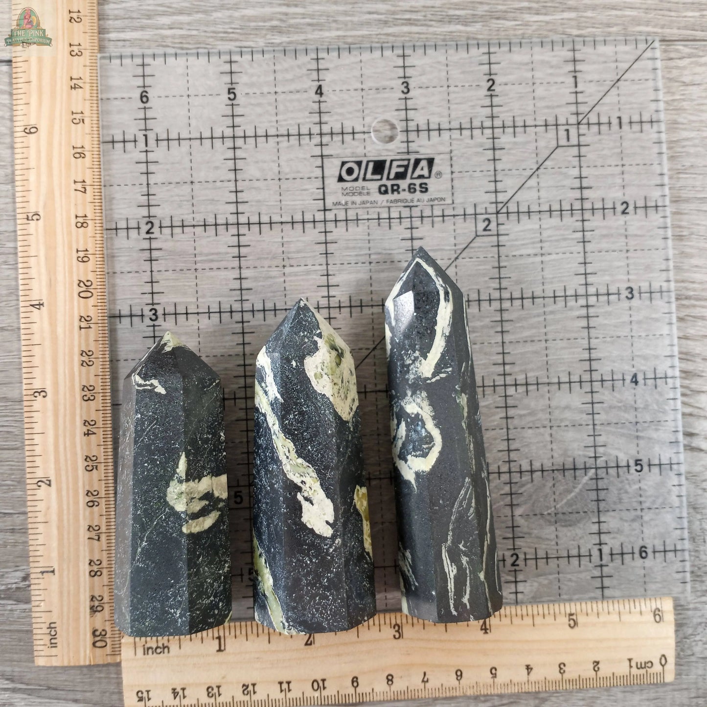 Three Keystone Crystals Coffee Bean Jasper Gemstone Obelisks (4 to 5 oz bulk crystal towers) are displayed upright on a clear OLFA quilting ruler, with wooden rulers along the left and bottom edges for scale.