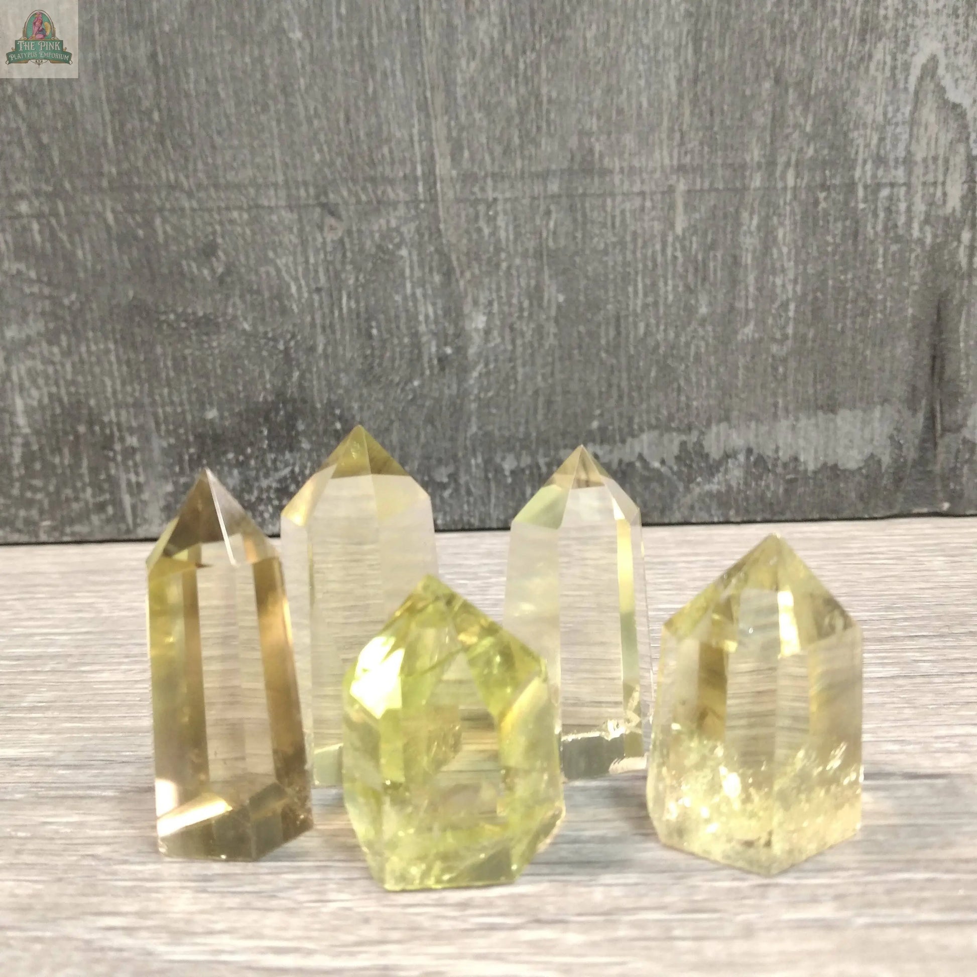 Five Coffee Bean Jasper crystal towers from Keystone Crystals, each weighing 4 to 5 oz, are arranged on a light wooden surface with a gray textured background.