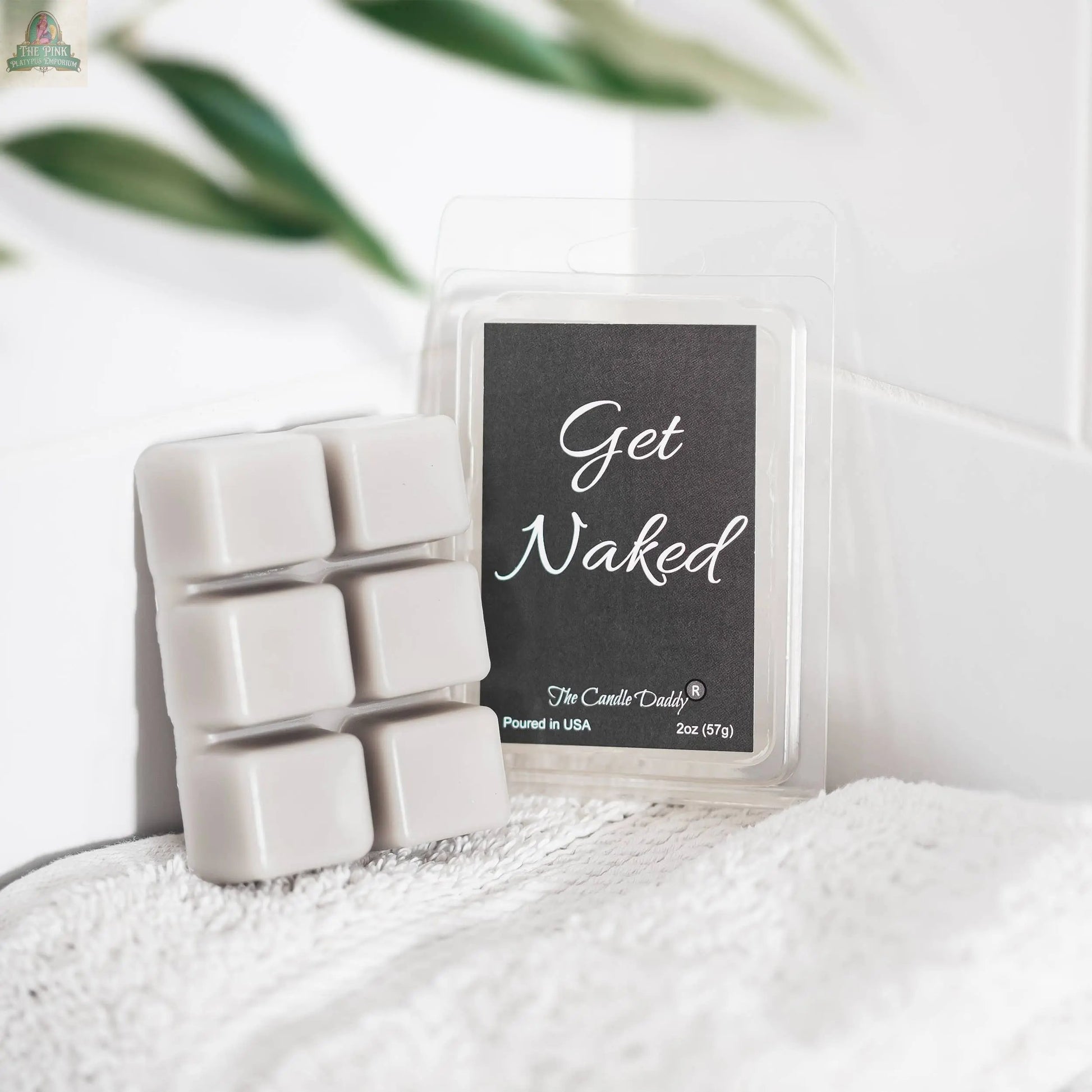 A pack of Get Naked - Mulled Cider & Chestnut Scented Wax Melts sits on a white textured towel, with green leaves softly blurred in the background.