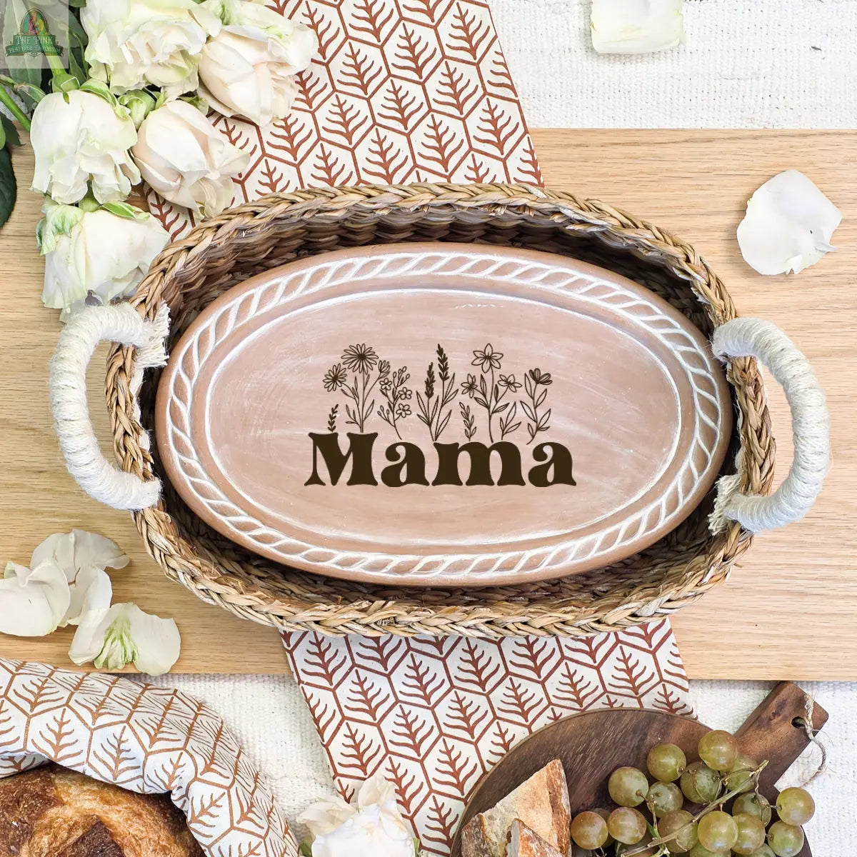 The Handmade Bread Warmer & Wicker Basket - Mom Oval : Design 3 features an oval wooden tray with white leaf designs and “Mama,” plus floral art. Surrounded by grapes and white roses, it’s the perfect gift for bread lovers on any special occasion.