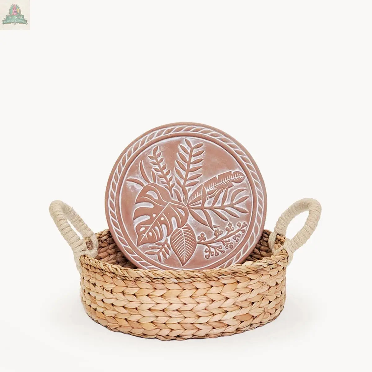 The KORISSA Handmade Bread Warmer & Wicker Basket - Plant Round features a round wicker basket with handles and a terracotta plate engraved with a botanical leaf design, shown on a plain white background.