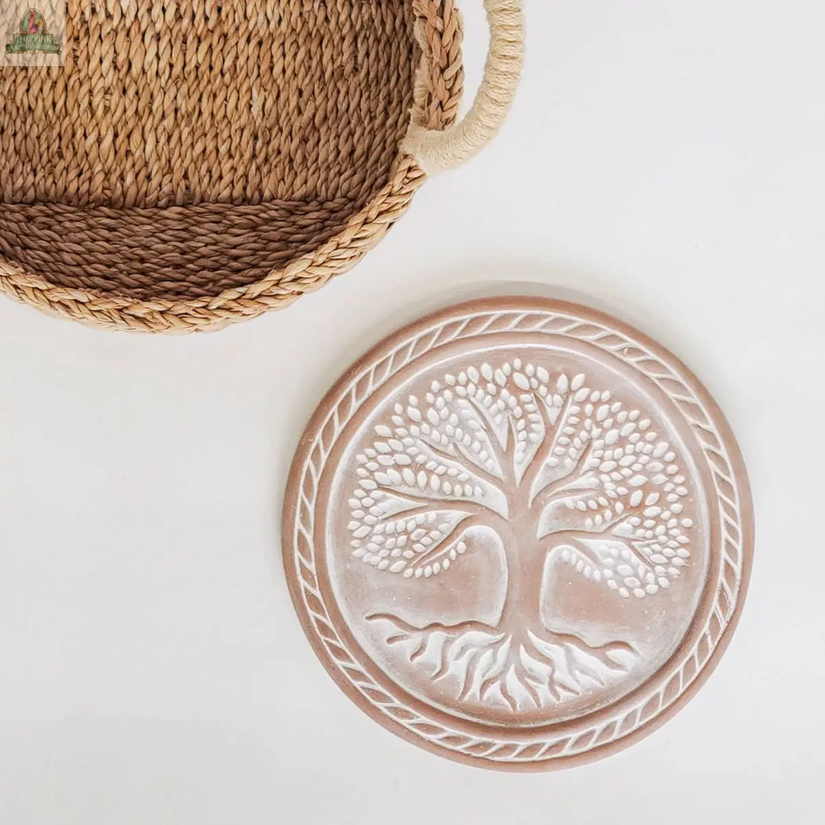 The KORISSA Handmade Bread Warmer & Wicker Basket – Tree of Life Round features a round wicker basket with handles and a ceramic bread warmer embossed with a tree design, perfect for keeping bread warm at your table.