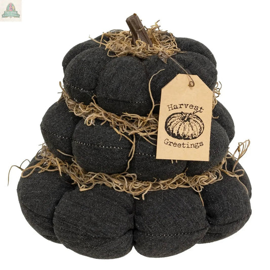 The Harvest Greetings Stuffed Pumpkin Stack features layered dark gray fabric pumpkins with straw accents, a small stem, and a tag reading "Harvest Greetings" with a pumpkin illustration—perfect rustic décor for autumn displays.