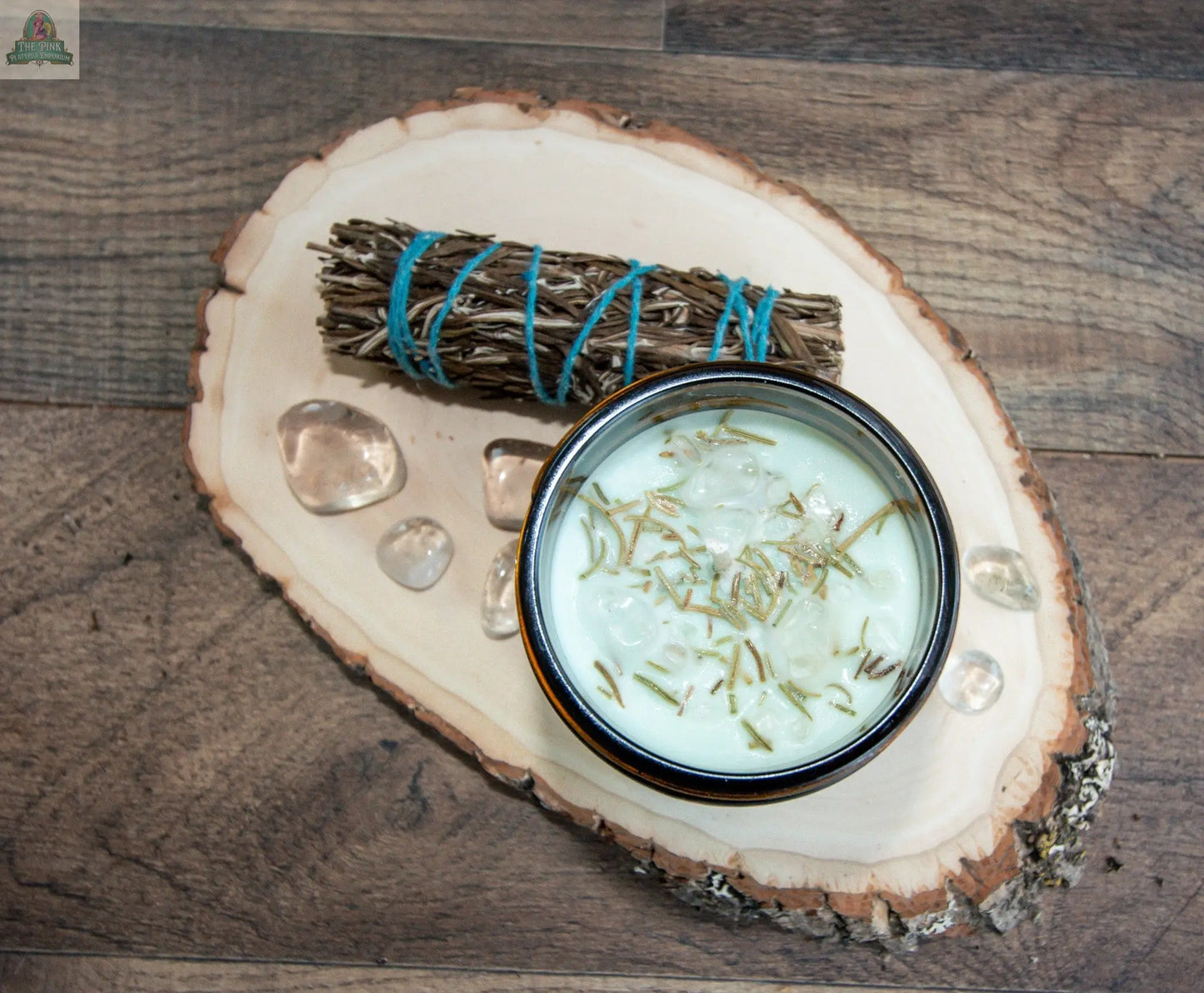 A wooden slab displays Healing: a bundle of dried herbs tied with blue string, clear crystals, and a bowl of creamy liquid topped with rosemary, creating the perfect mood for an energy clearing candle ritual.