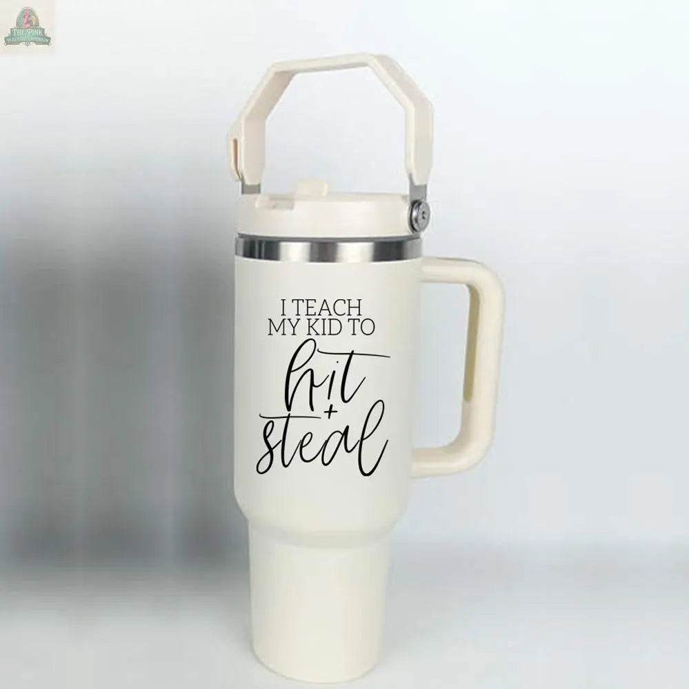 The Hit & Steal is a large white 40oz tumbler with a handle and lid, featuring black script text that says "I Teach My Kid to Hit + Steal" on a plain, light background—perfect for any baseball mom.