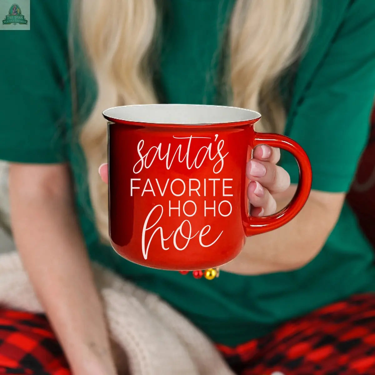 A person in green and red holiday pajamas holds the Ho Ho Hoe Mug, a red ceramic campfire mug with white text reading "Santa's favorite ho ho hoe.