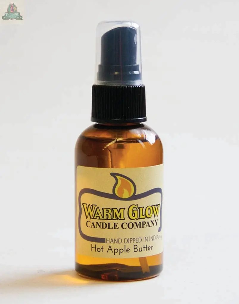 A small amber spray bottle labeled Warm Glow Candle Company features Hot Apple Butter Atomizer Oils, hand dipped in Indiana. With a black spray top, it's perfect for refreshing Warm Glow potpourri.