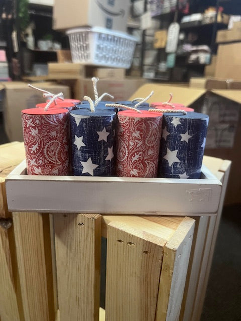 Stack of firework rolls with star and stripe patterns on a wooden shelf.