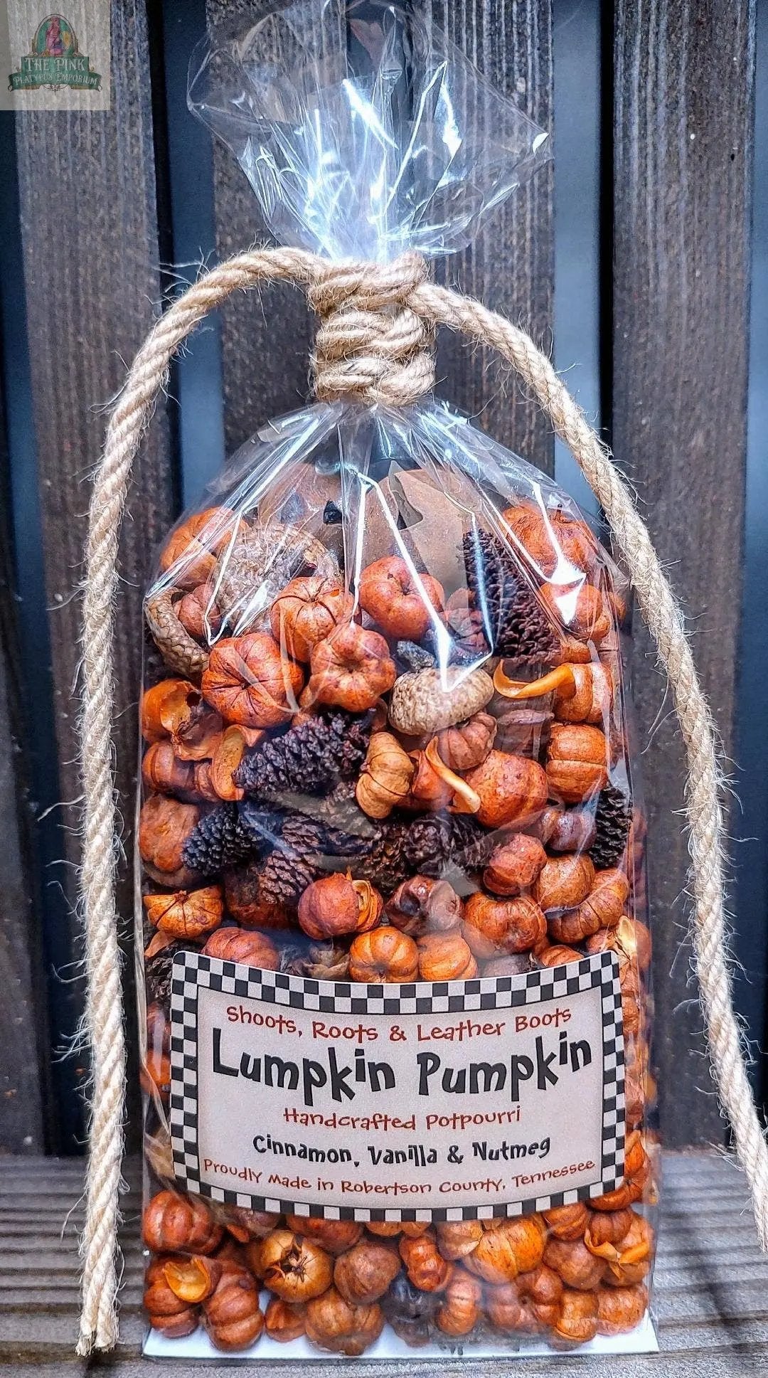 A clear plastic bag of 'Lumpkin Pumpkin' Handcrafted Potpourri—5 cups, tied with rope, sits on wood. The label features cinnamon, vanilla & nutmeg: a perfect bowl filler for home fragrance.