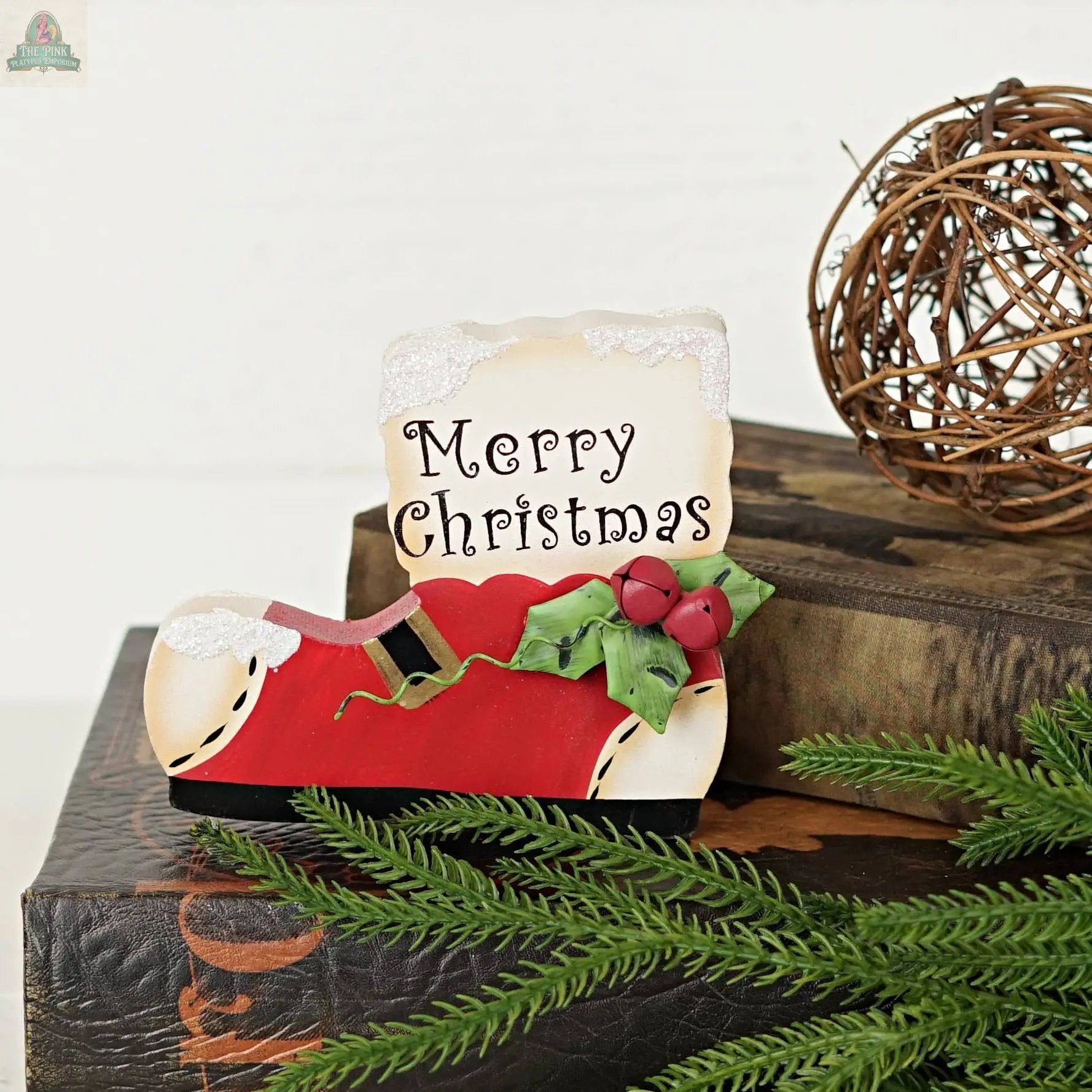 The Impressive Enterprises, Inc. Wood Red/White Snow Boot sign (5" x 4.25") adds festive charm to your décor with its bright red boot shape and "Merry Christmas" text—perfect for holiday displays or tabletops.