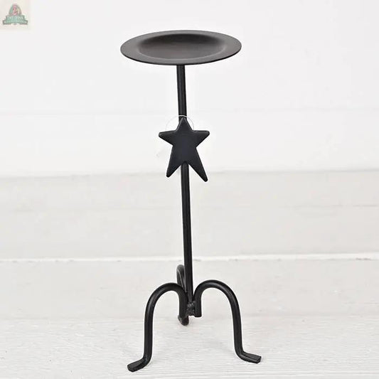 The Forged Iron Candle Holder features a black finish, round plate top, hanging star ornament, and three curved legs—perfect as an elegant tabletop accent on light surfaces against a white background.
