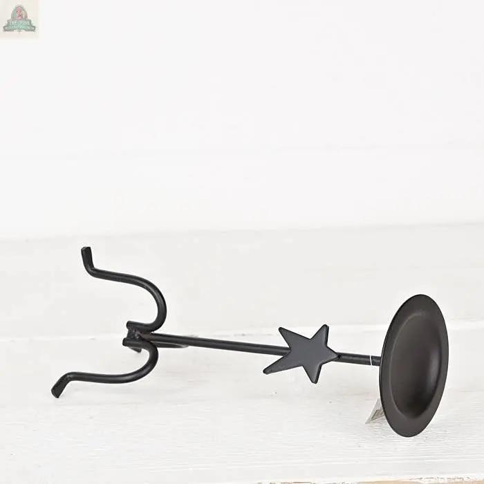The Forged Iron Candle Holder features a black metal stand with a star accent, a round flat plate on one end, and two curved hooks on the other—ideal as a tabletop decoration or candle holder, shown on a plain white background.
