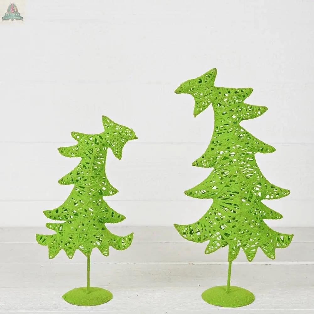 A whimsical 17-inch Grinch Fairy Tree by Impressive Enterprises, Inc. stands on a round base, with its lacy, light green flocked design and wavy silhouette reminiscent of holiday decor against a white wooden backdrop.