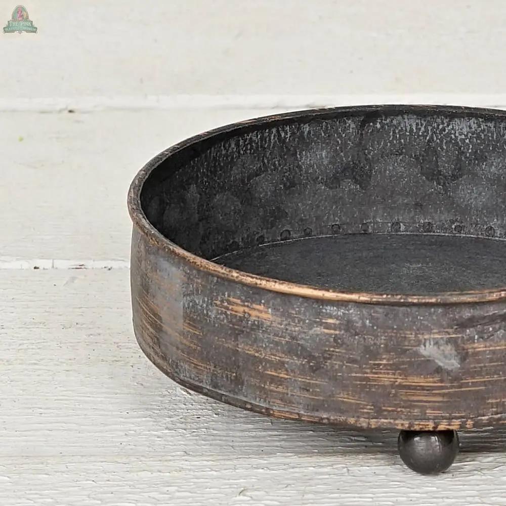 The Antique Pewter metal round Bowl container (6.5inD) by Impressive Enterprises, Inc. has a rustic weathered finish and sits on three ball feet—an ideal decorative centerpiece, partially shown on a white wooden surface in the image.