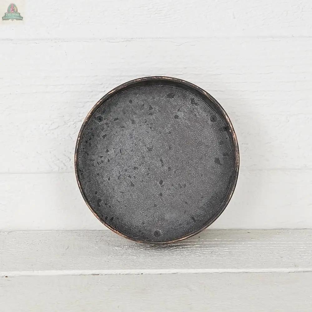 The Antique Pewter metal round Bowl container (6.5inD) by Impressive Enterprises, Inc. makes a striking centerpiece when displayed on a white wooden surface with a matching background.