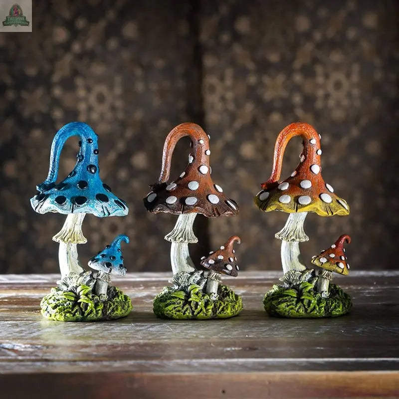 The Magic Mushroom Toadstools Home and Garden Decor Set of 3 features whimsical blue, brown, and orange toadstool clusters with white spots on mossy green bases—perfect cottagecore decor for any wooden surface.