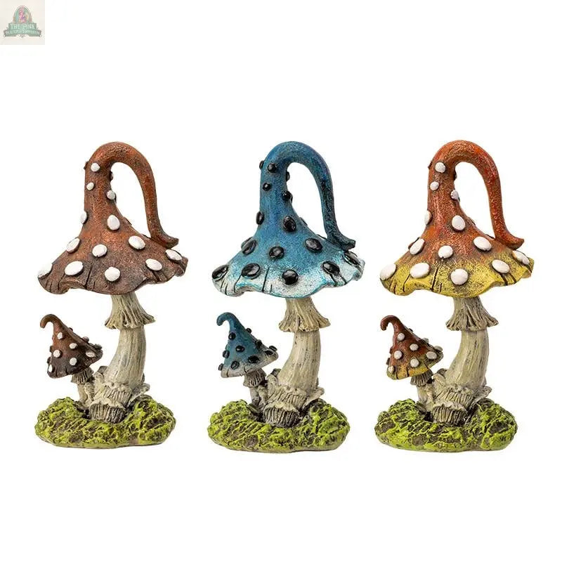 The Magic Mushroom Toadstools Home and Garden Decor Set of 3 features brown, blue, and orange-yellow statues with white spots on green grassy bases—whimsical, playful accents perfect for decorating your home or garden.