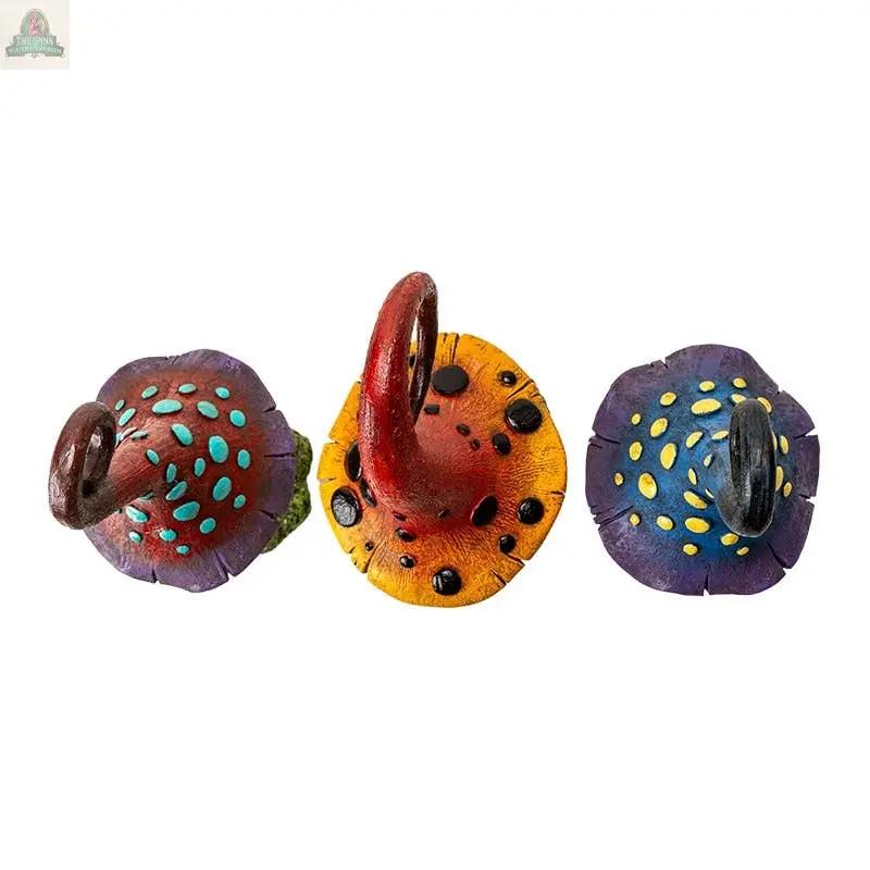 The Magic Toadstool Mushrooms Home and Garden Decor features three vibrant, whimsical mushroom statues in red, yellow, and purple with curled stems and spotted caps—perfect for cottagecore style—arranged side by side on a white background.