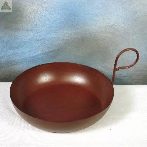 A burgundy Metal Gravy Pan candle holder with a curved handle is displayed on a white surface, set against a blue and gray background.