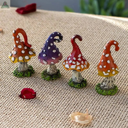 The Mini Magic Toadstool Mushroom Home and Garden Decor Set of 4 features whimsical, colorful statues with white spots and curly caps in orange, purple, red, and orange-red—ideal as fairy figurines or unique garden accents.
