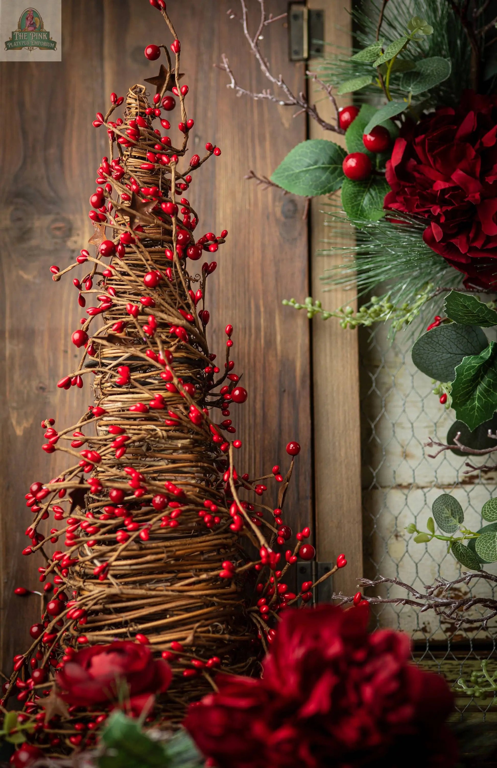 The 17" Mixed Berry Cone Tree with Rust Stars features woven twigs and red berries, set on a 5.25" base—perfect as a festive centerpiece beside any seasonal floral arrangement or rustic holiday decor.