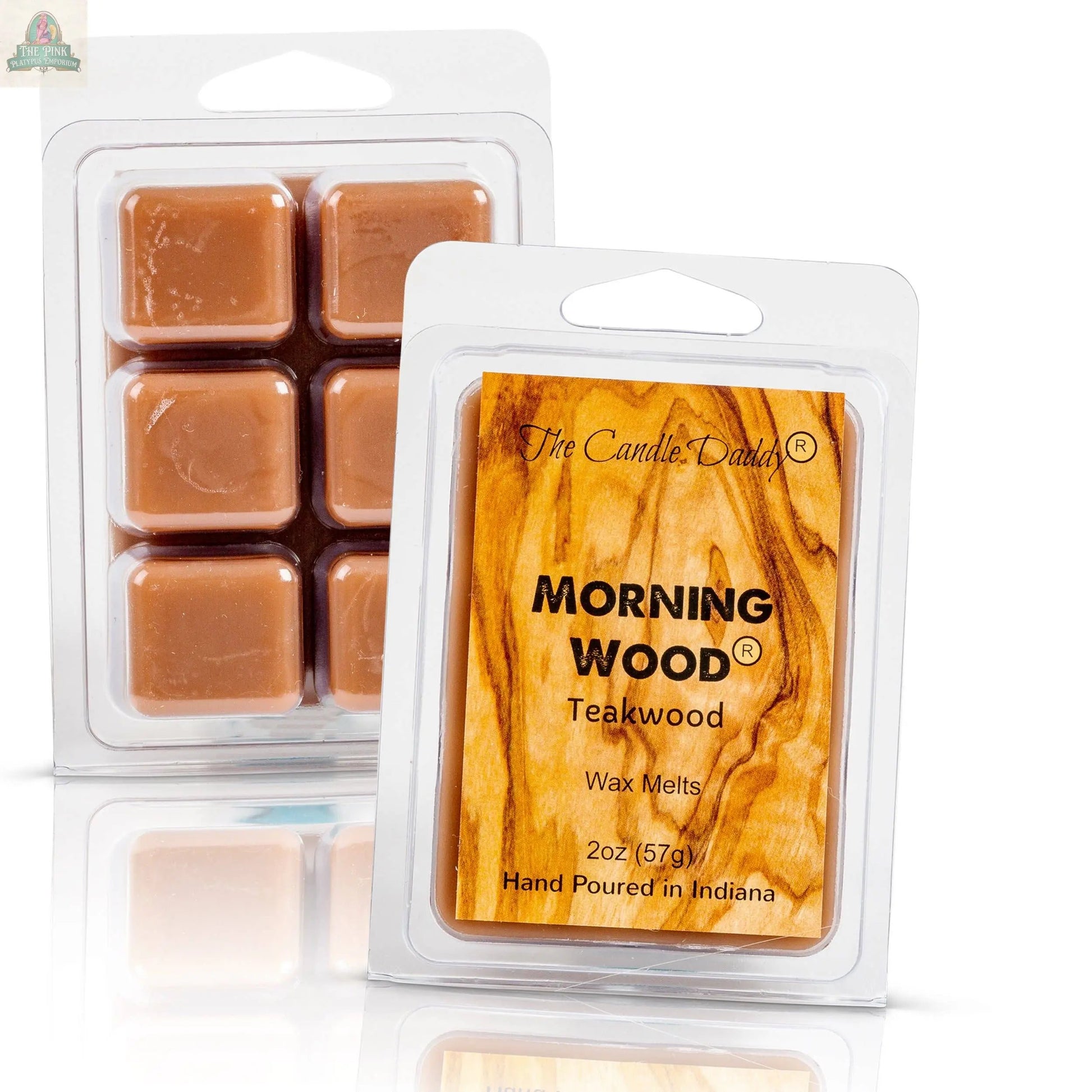 Two plastic clamshell packs of Candle Daddy wax melts are shown, labeled "Morning Wood - Teak Wood Scented Wax Melt," hand-poured in Indiana, with a wood grain background highlighting their strong teakwood scent.