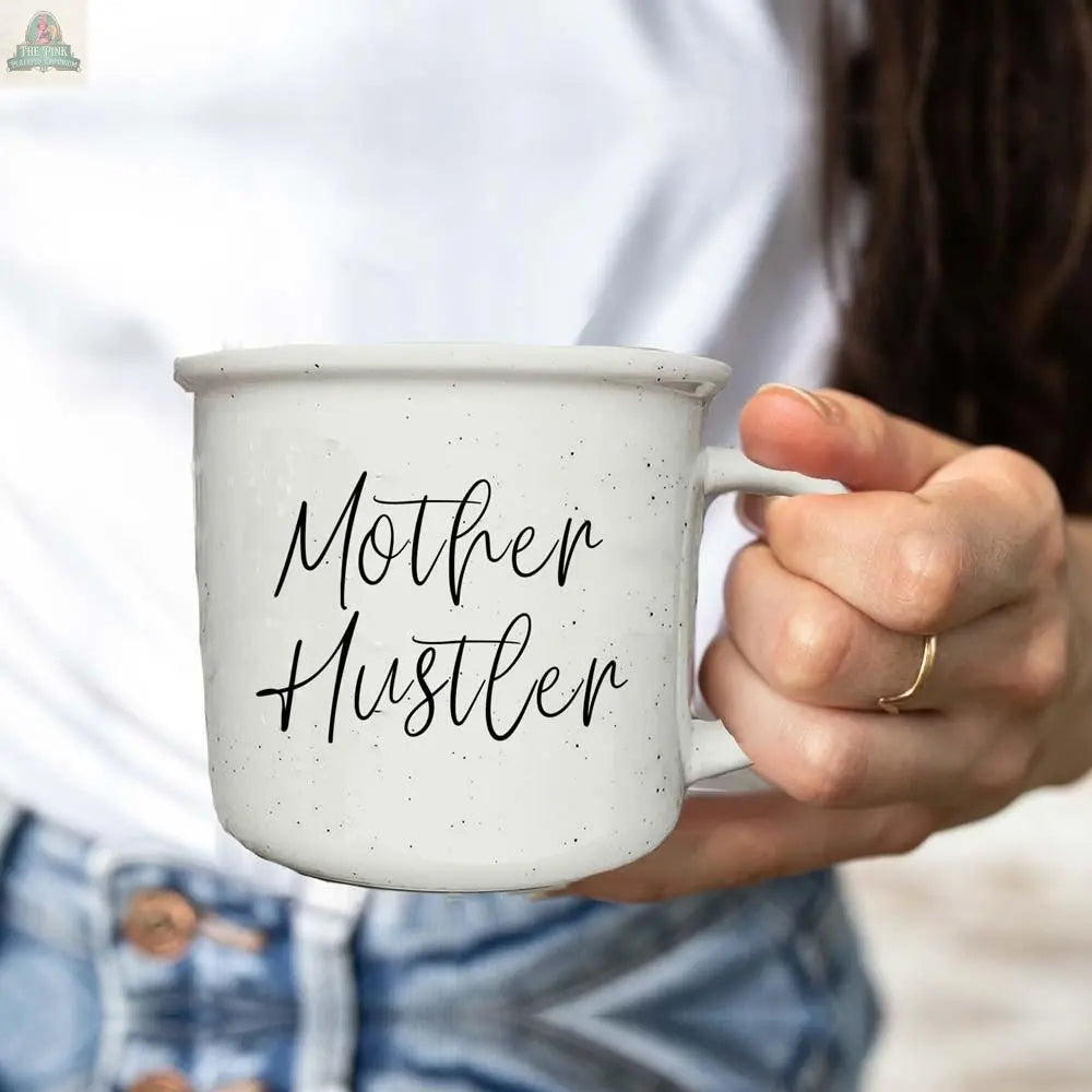 Someone in a white shirt and jeans holds the Mother Hustler 14.5oz white speckled mug, featuring "Mother Hustler" in black script.