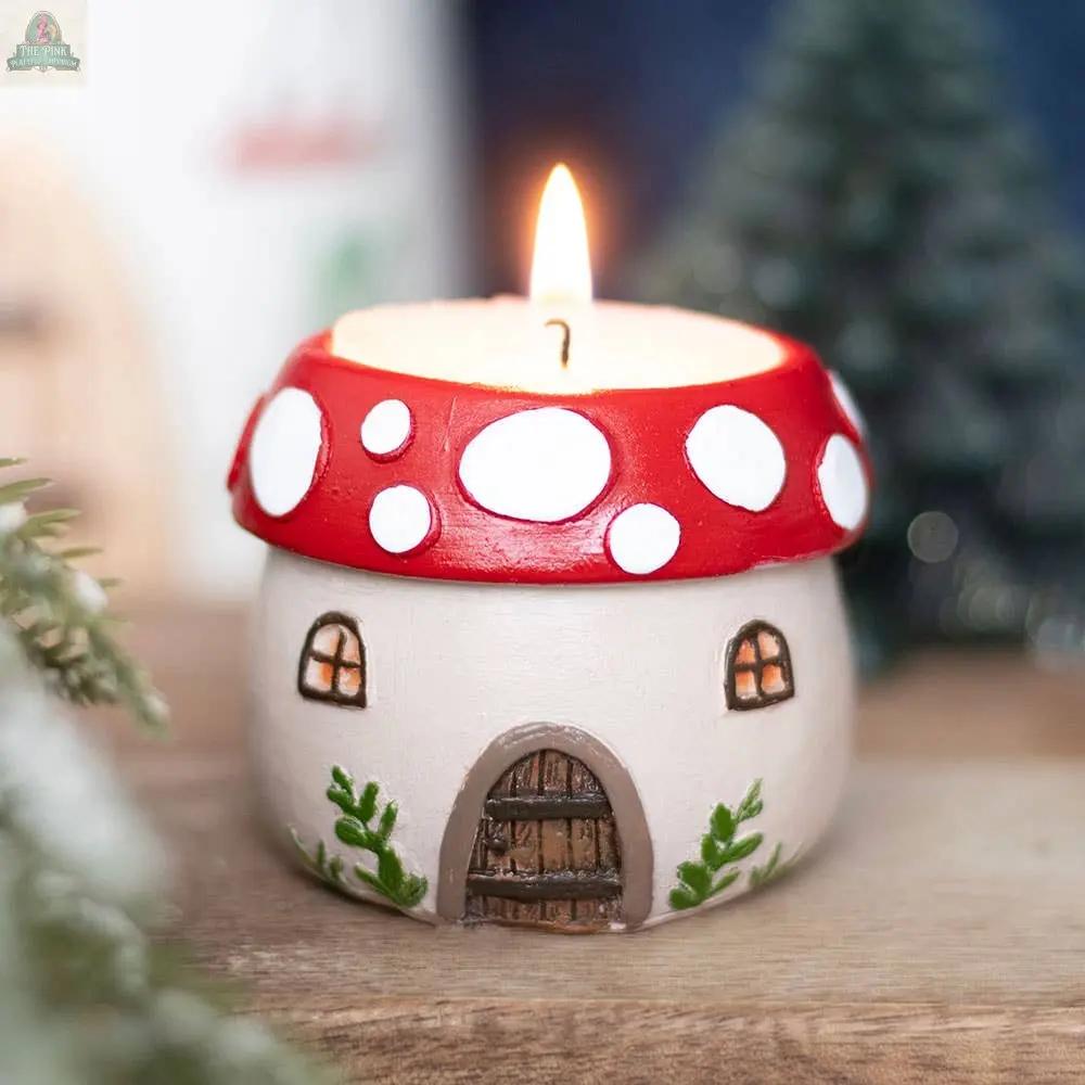 The Mushroom House Resin Tealight Holder features a red top with white spots, tiny windows, a brown door, and green accents—perfect as whimsical winter forest home decor.