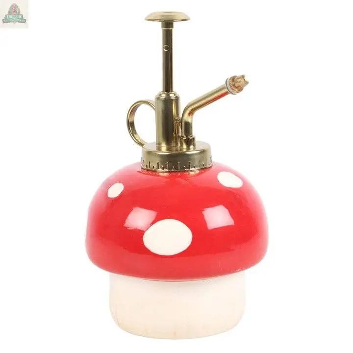 The Mushroom Shaped Plant Mister features a red and white mushroom base with a gold metal pump, perfect for adding cottagecore charm to your indoor garden decor.
