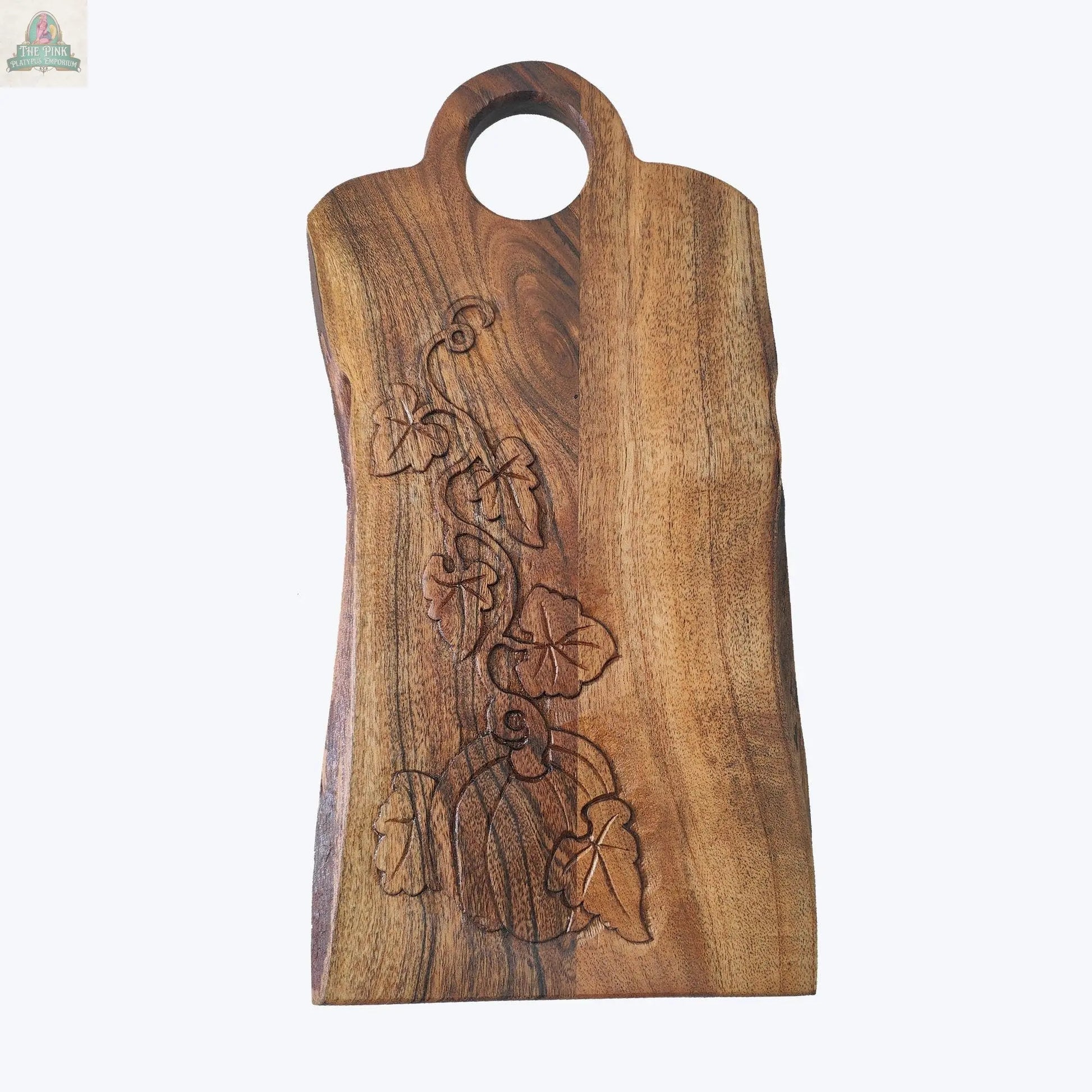 The Young's Natural Wood Charcuterie Board With Carved Pumpkin Design features a rounded handle and displays an intricate pumpkin, leaves, and vines carved on its surface.