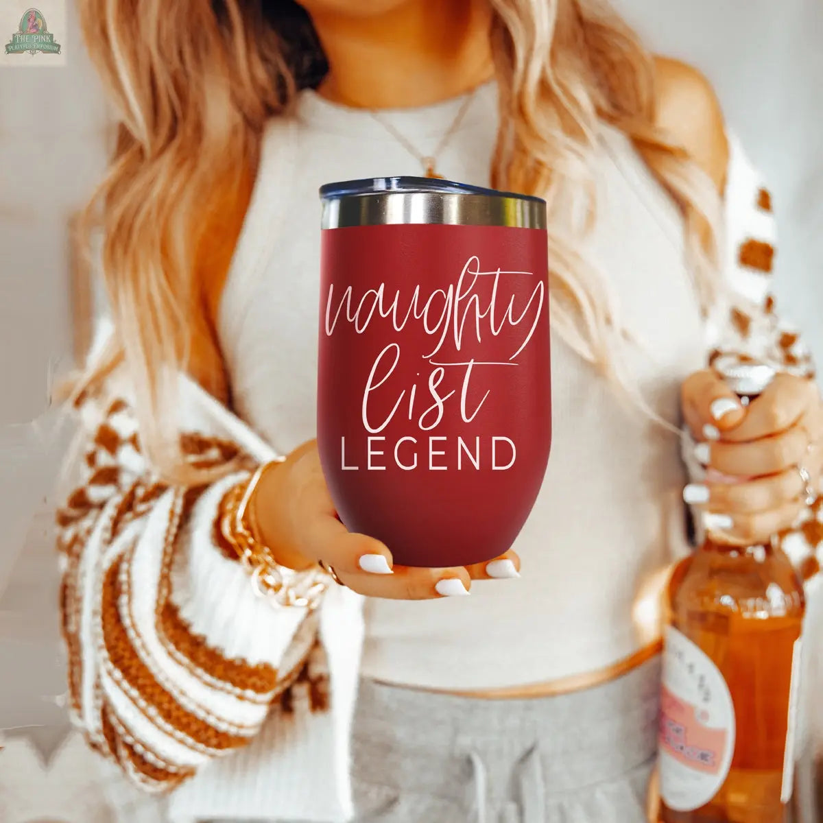 A woman holding a Naughty List 17oz stainless steel tumbler.