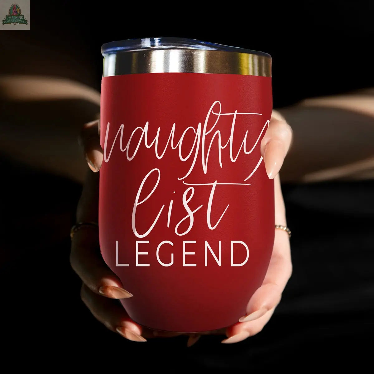 A person holds the Naughty List 17oz red stainless steel tumbler with a silver rim. White script reads “naughty list LEGEND,” and the dark background highlights the wine tumbler’s playful design.