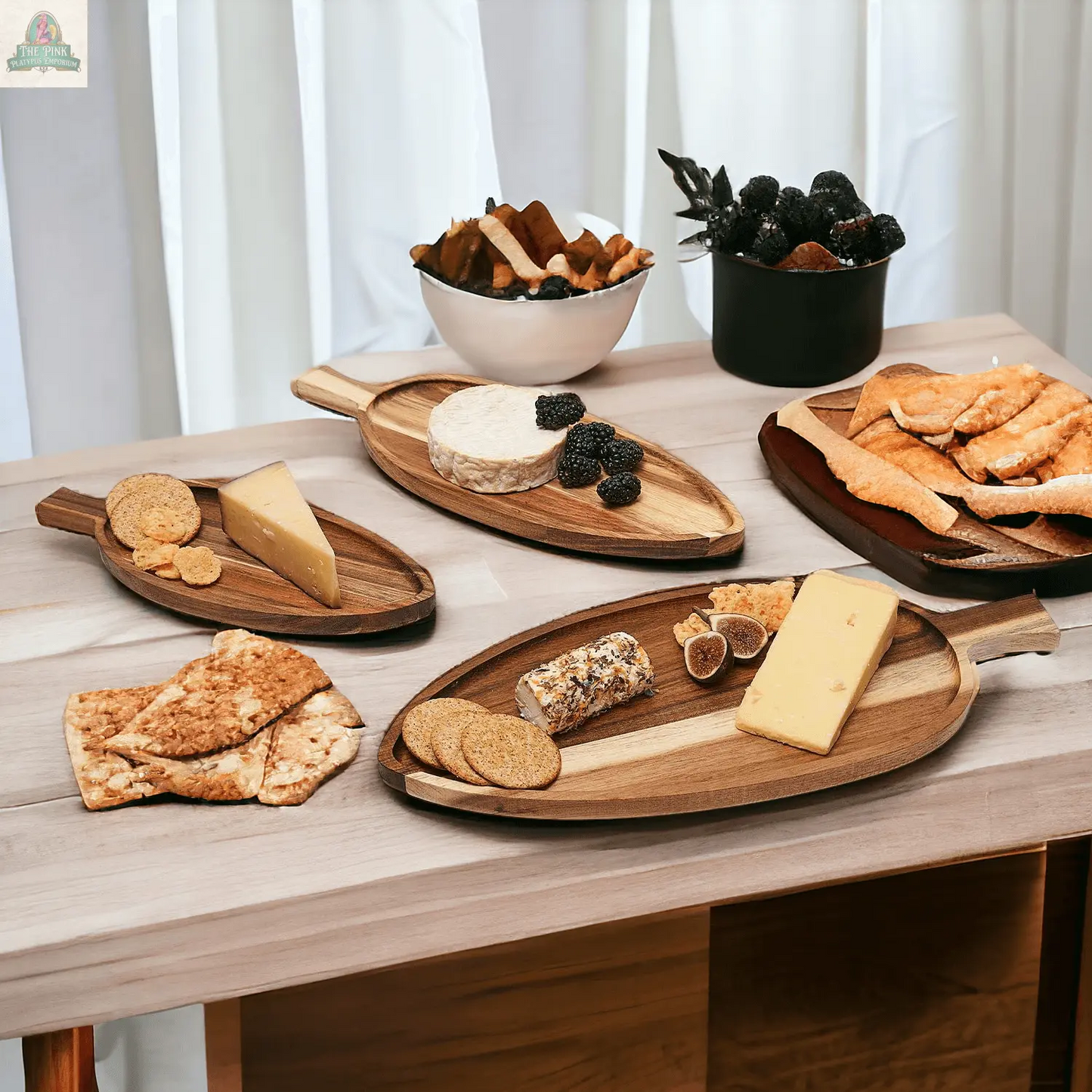 A table set with Nesting Trays | 3 Sizes, displaying assorted cheeses, crackers, and fruit. Bowls of dried fruit and croissants sit in the background on a light wooden surface by a white curtain.