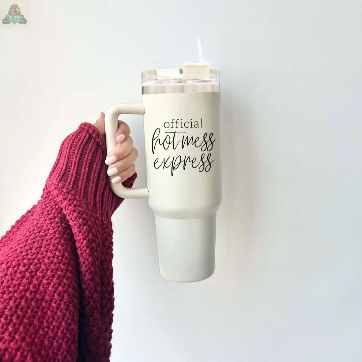 A hand in a chunky red sweater holds the Official Hot Mess 40oz tumbler with a straw. The insulated white cup features "Official Hot Mess Express" in bold black script.