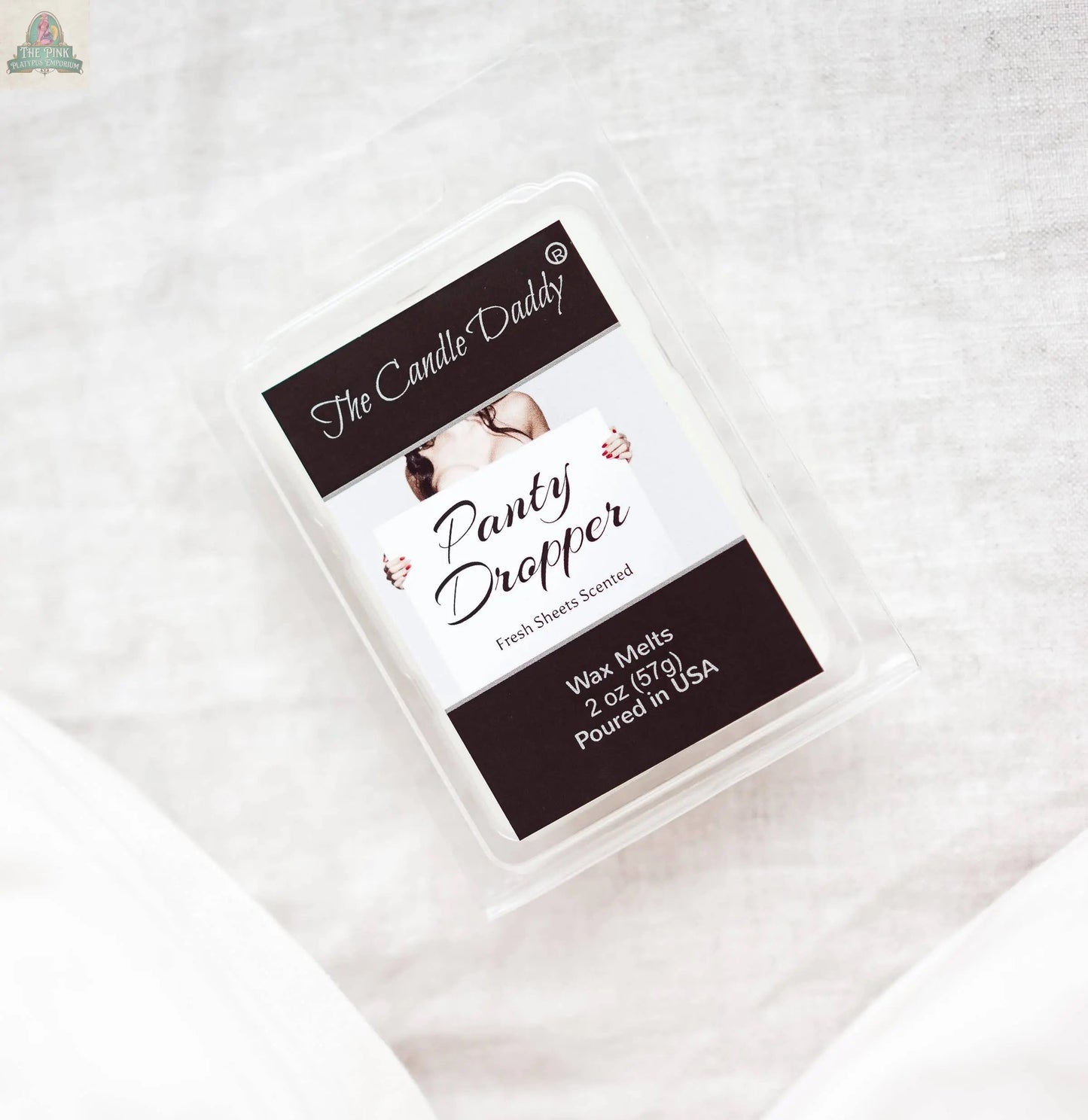 A plastic clamshell labeled “PANTY DROPPER - FRESH BED SHEETS SCENTED MELT - 1 PACK 2 OZ” sits on white fabric, ideal for fans of fresh bed sheets fragrances and relaxing wax melts.