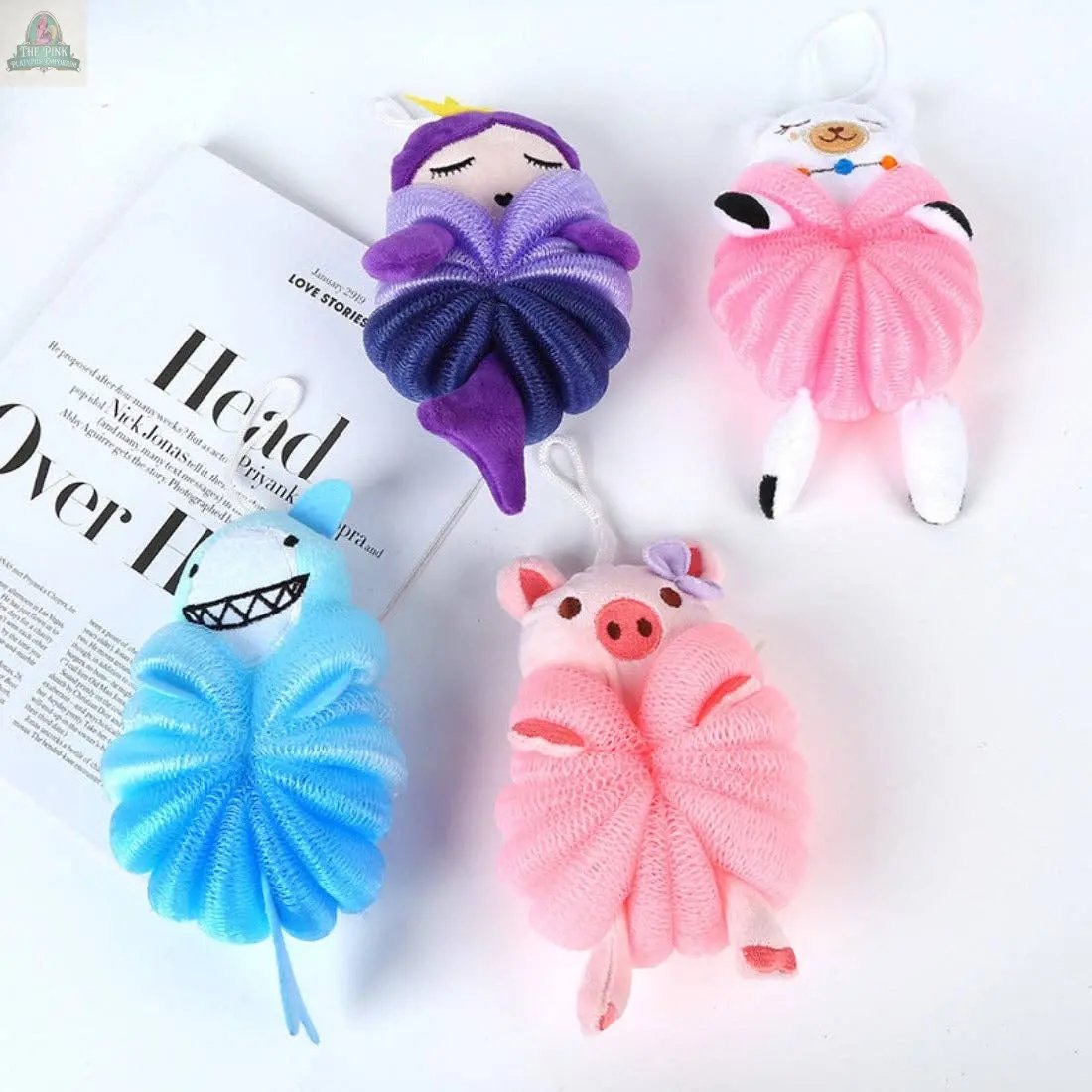 The PAPO Cute Cartoon Bath Sponge: Pig is a fun and colorful bath sponge for kids, shaped like a pink pig to make bath time enjoyable. It’s shown on a white surface beside an open magazine.