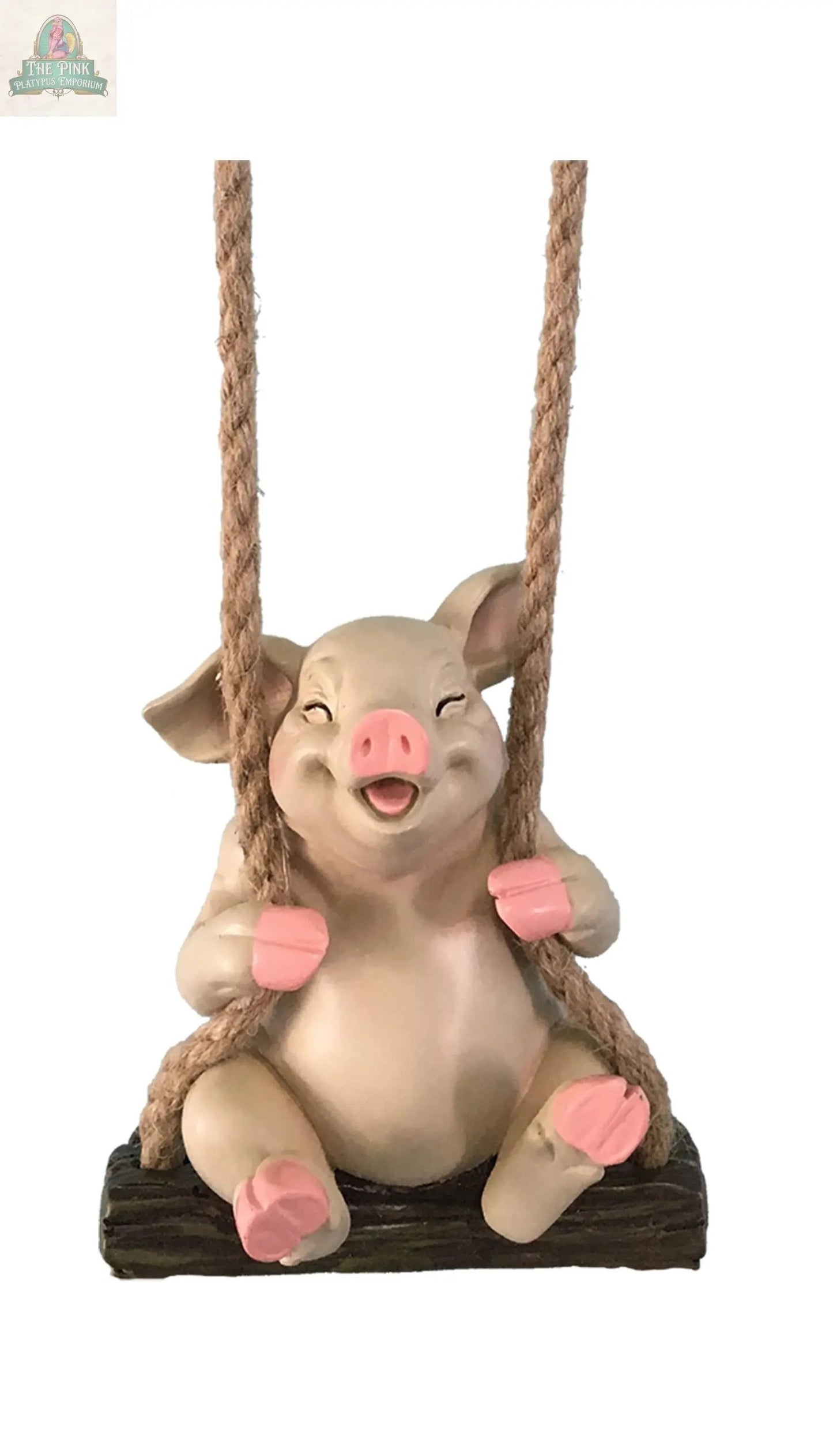 The PIG SWINGER is a handcrafted figurine with pink ears, snout, and hooves, sitting cheerfully on a wooden swing with thick rope. Ideal for outdoor décor, this playful piece adds charm and stands out against any plain white background.