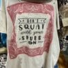 T-shirt with text saying "don't squat with your spurs on" design on a plain background