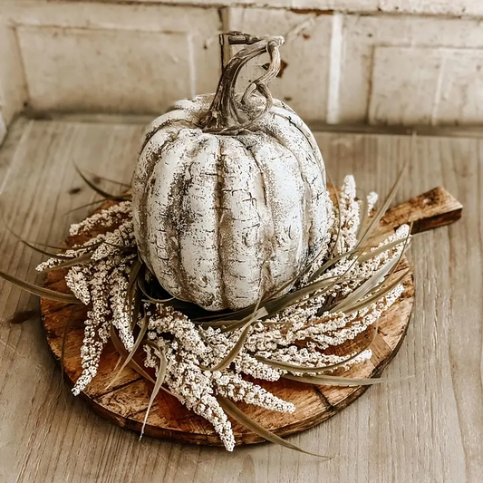 Decorative white pumpkin on a wooden board with wheat on a rustic wooden surface
