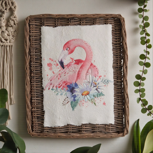 Floral and flamingo design on a piece of paper inside a woven frame, with plants around.
