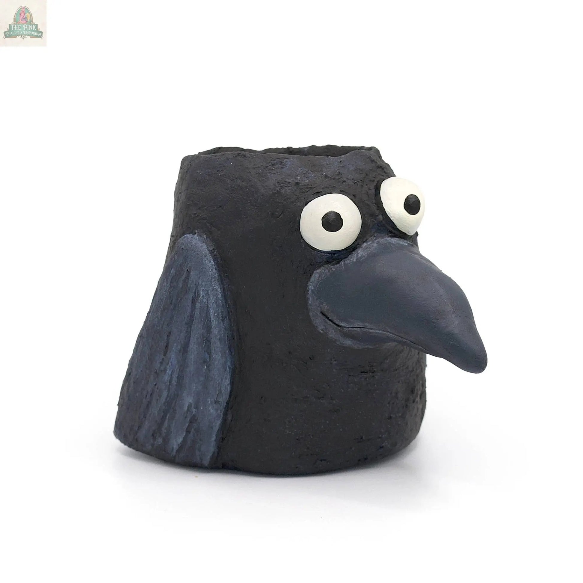 Poe the Crow Blobhouse Planter is a small, handmade poly-resin sculpture with a large beak, wide white eyes, and textured wings. This charming black bird doubles as a planter—perfect for adding unique style to your home décor.
