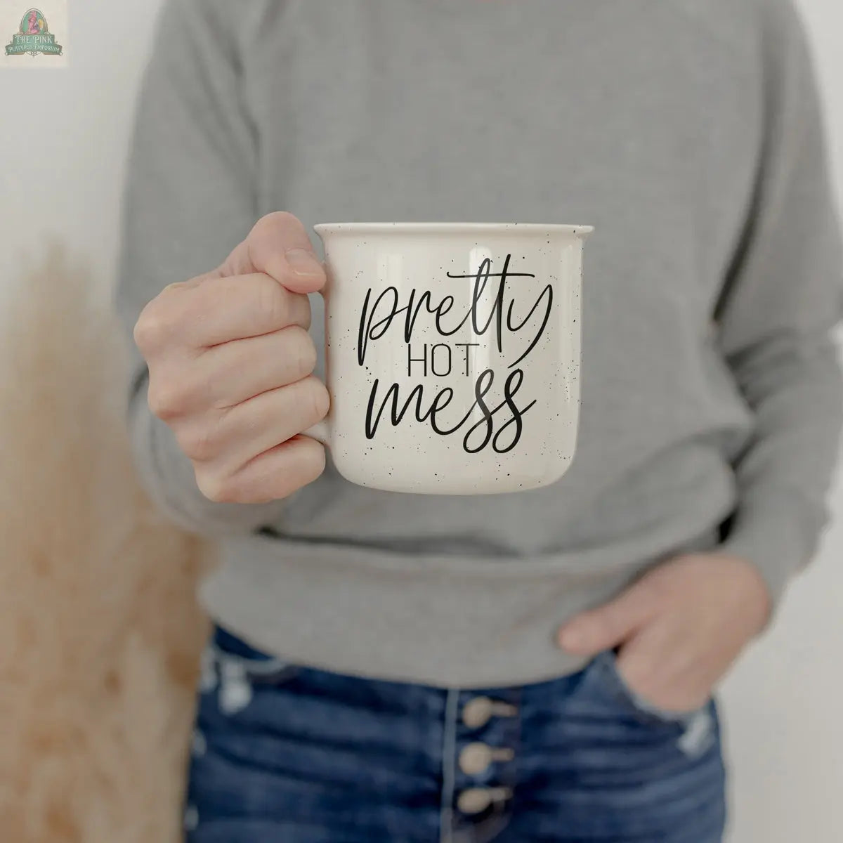 Someone in a grey sweater and jeans holds the Pretty Hot Mess 14.5oz ceramic mug featuring black text. The background is neutral and softly blurred.